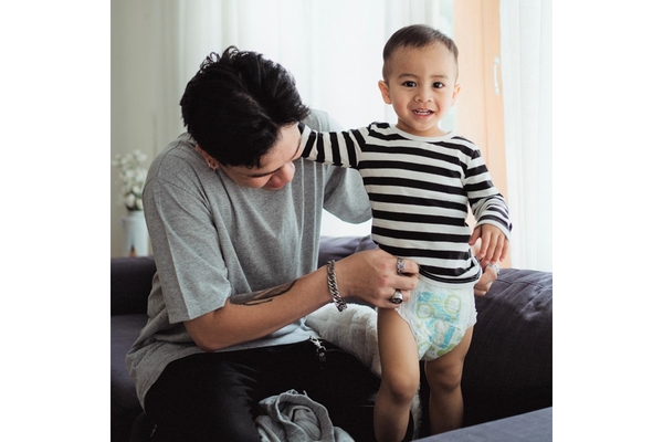 A father putting on his sons diaper.